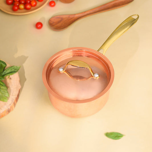 Copper saucepan with a gold handle on a beige background