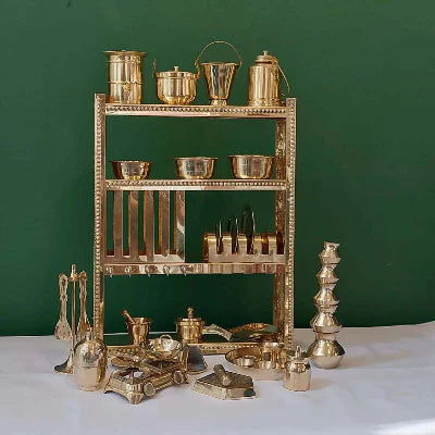 Collection of gold kitchen utensils on a white surface with a green background