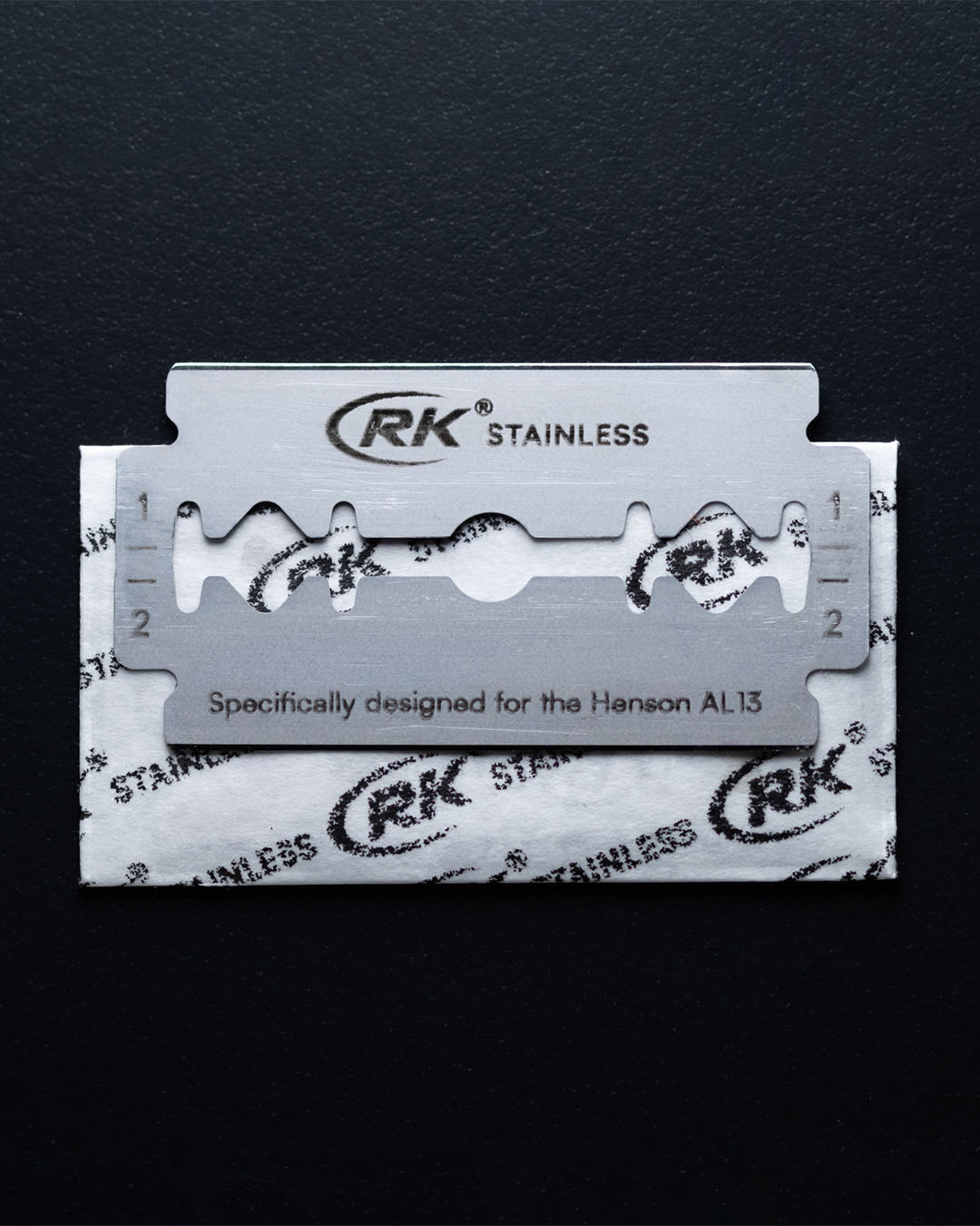 RK stainless steel razor blade on a black background